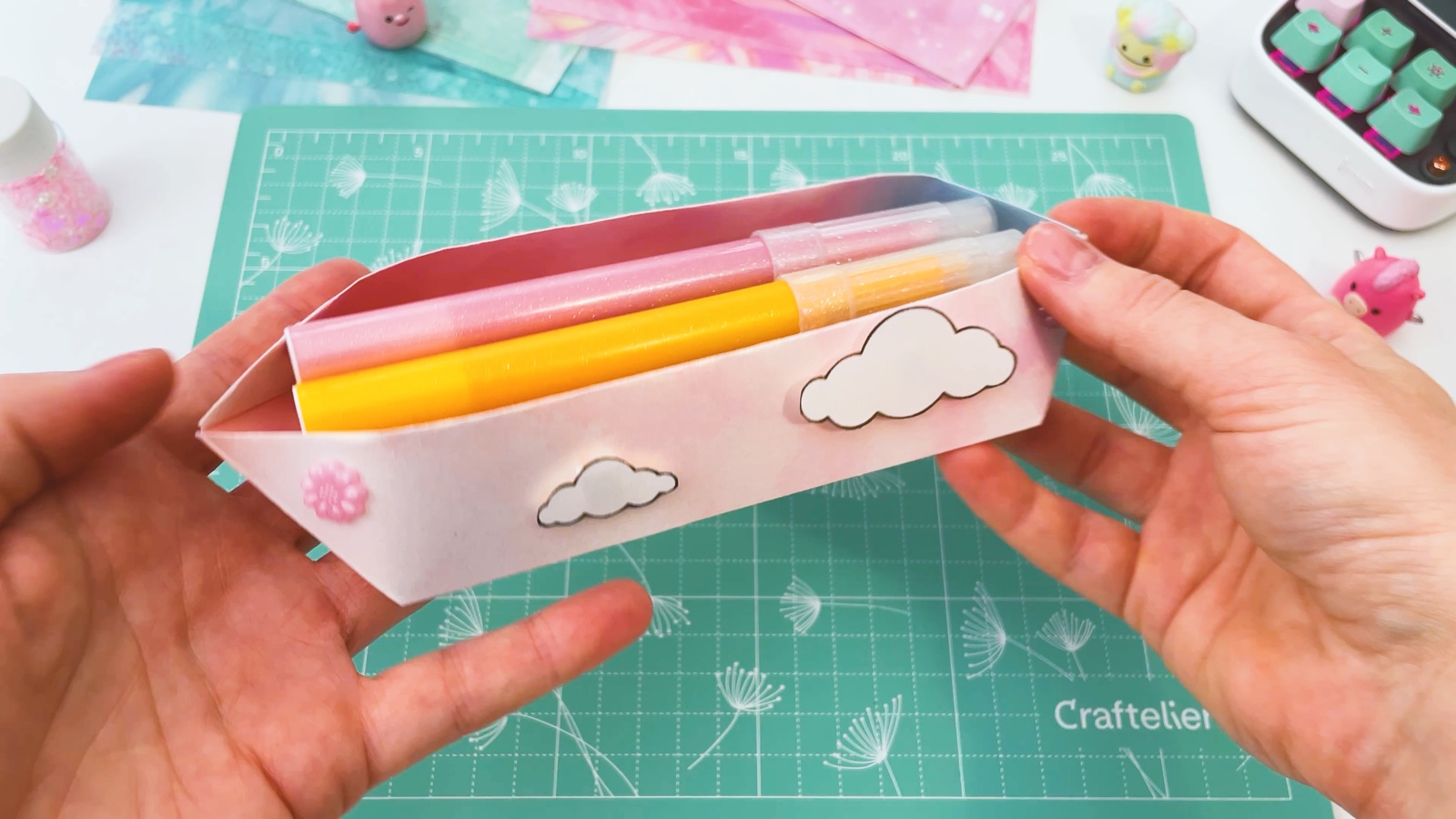Holding the open pencil case with a pink and a yellow marker inside