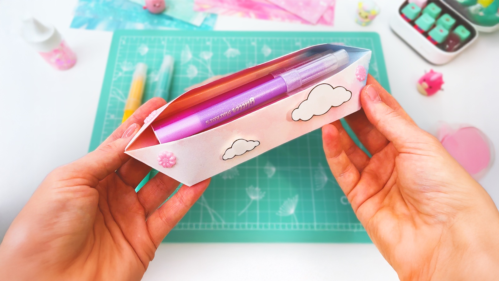 A finished pastel paper pencil case with cloud stickers, holding glitter markers