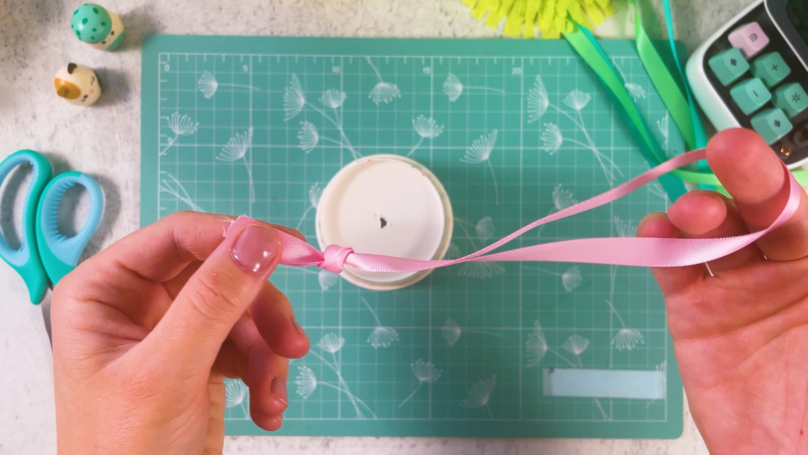 Tying the two ends of a pink ribbon into a knot to make a loop