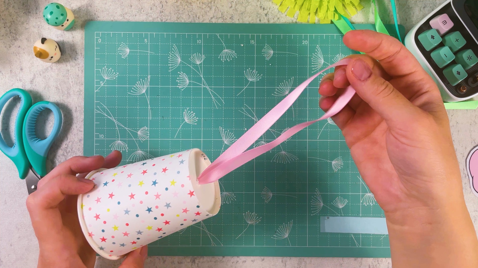 Pulling the pink ribbon loop out through the hole in the bottom of the cup