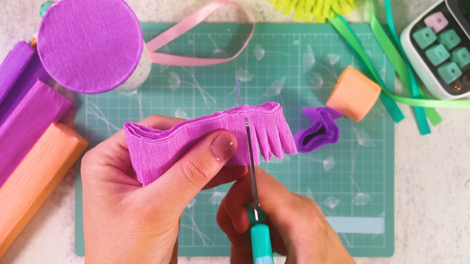 Cutting a fringe into a folded strip of pink crepe paper