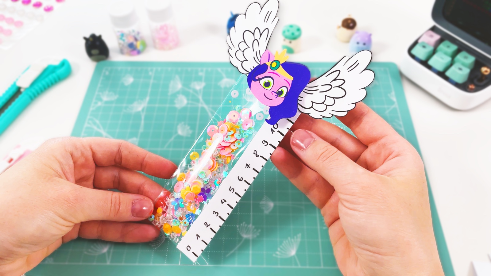 Finished sparkly shaker ruler full of pastel sequins, with Pipp Petals’ head and white wings on top
