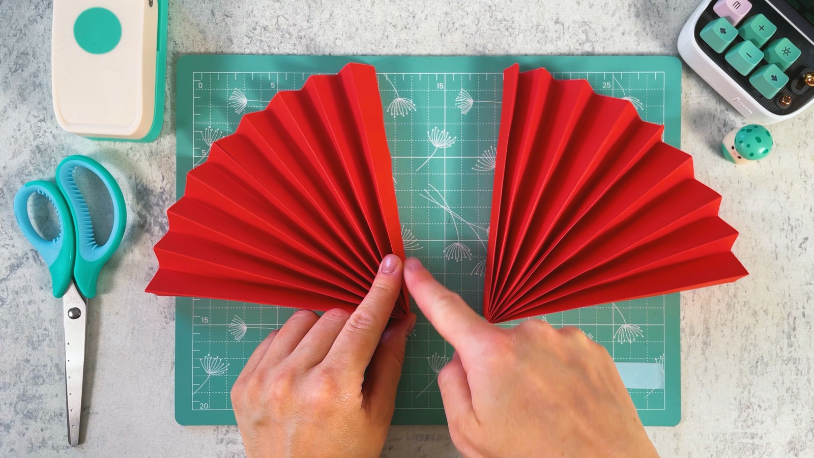 Dos abanicos de papel rojo uno al lado del otro sobre el tapete de corte