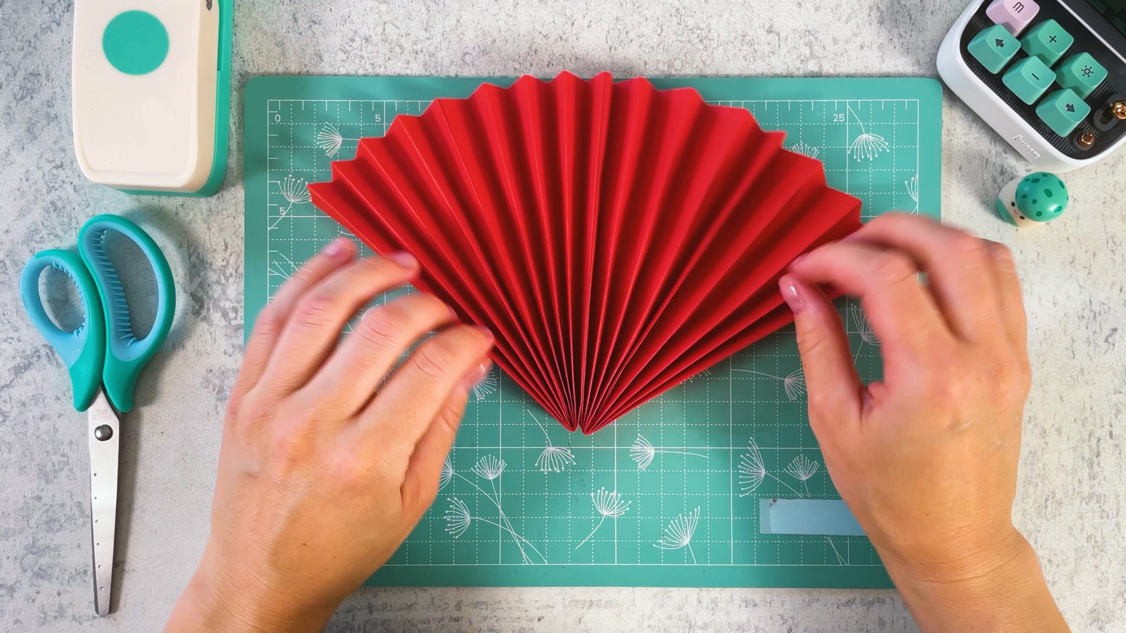 Abriendo los dos abanicos rojos pegados en un medio círculo rojo