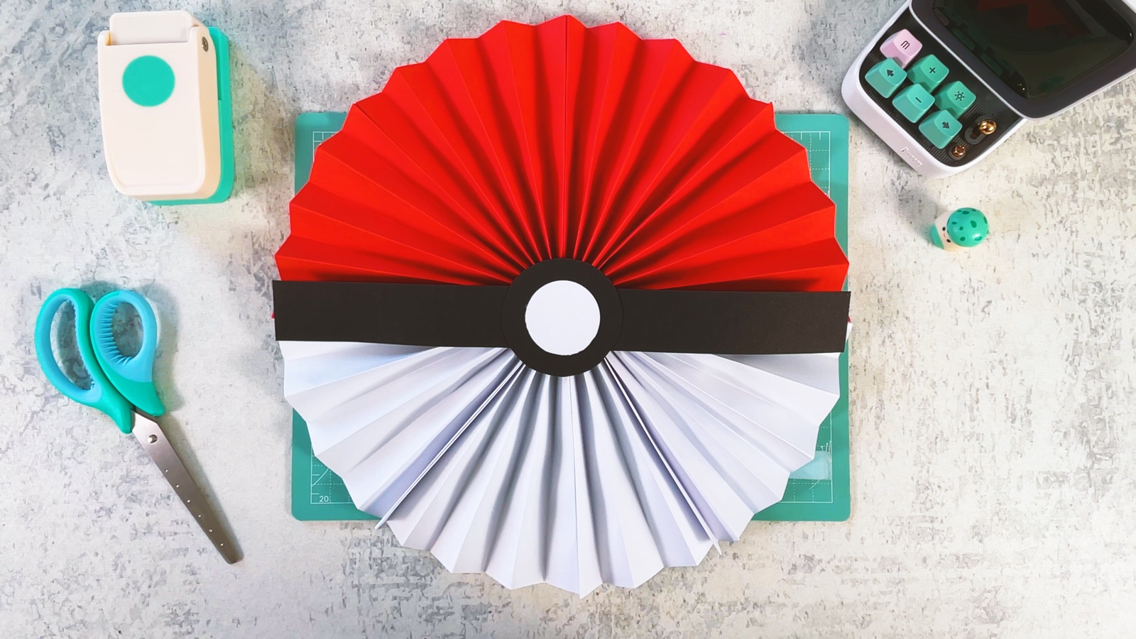 Finished paper Poké Ball rosette, red and white pleats with a black band and white button