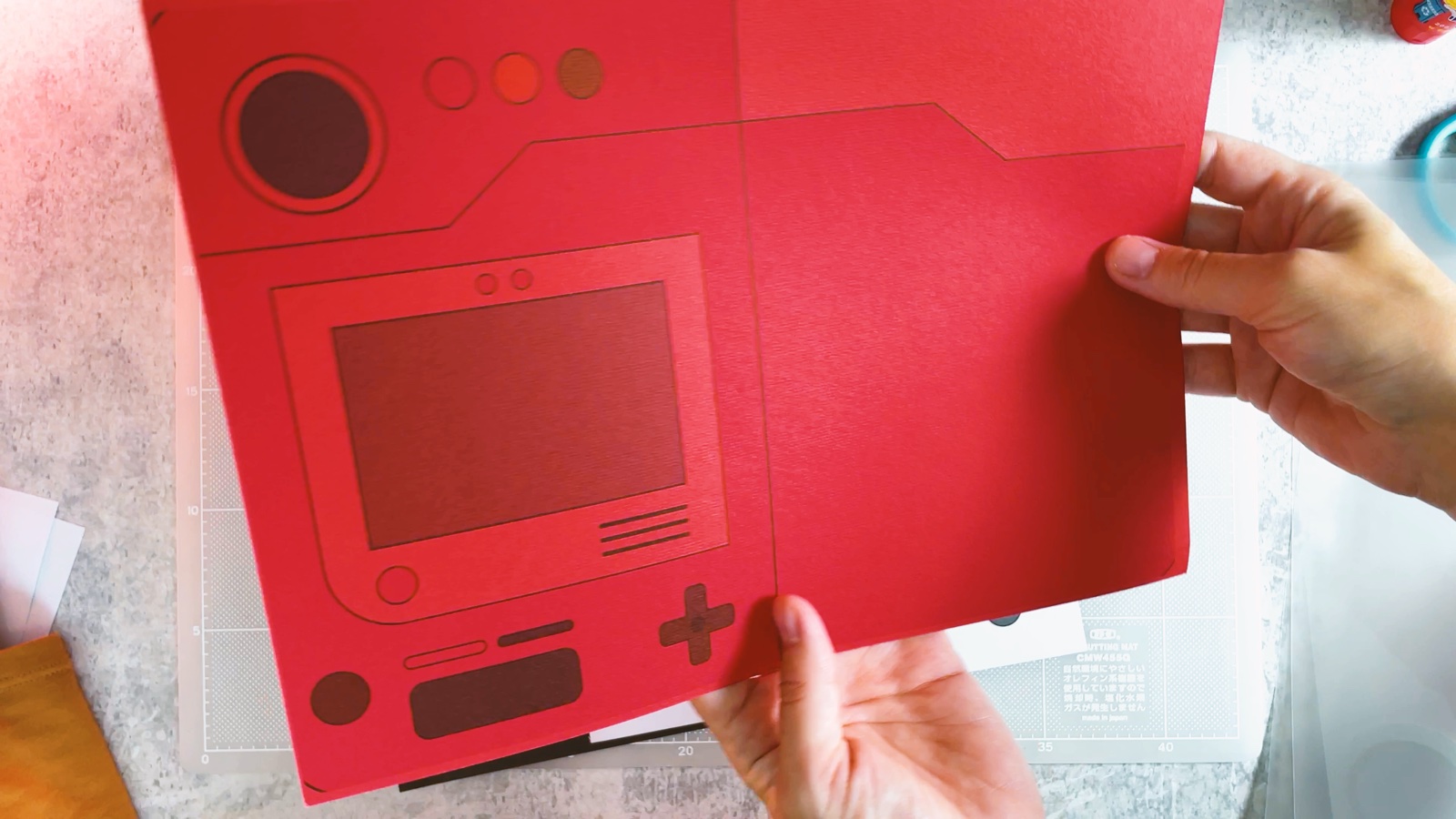 Una hoja impresa con el Pokédex rojo sostenida sobre el tapete de corte