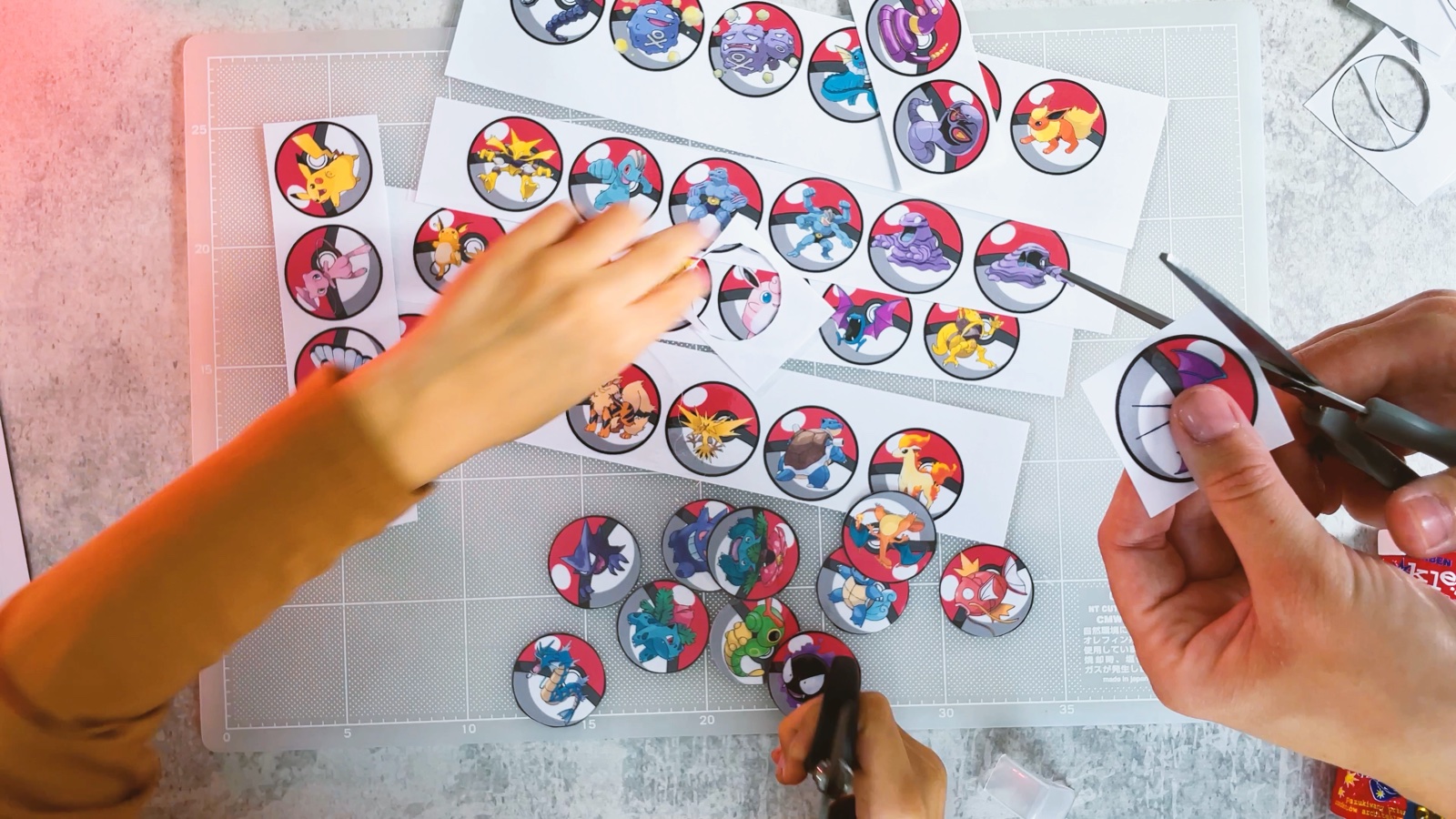 Recortando una ficha redonda de Pokémon de una tira plastificada, con fichas ya recortadas debajo