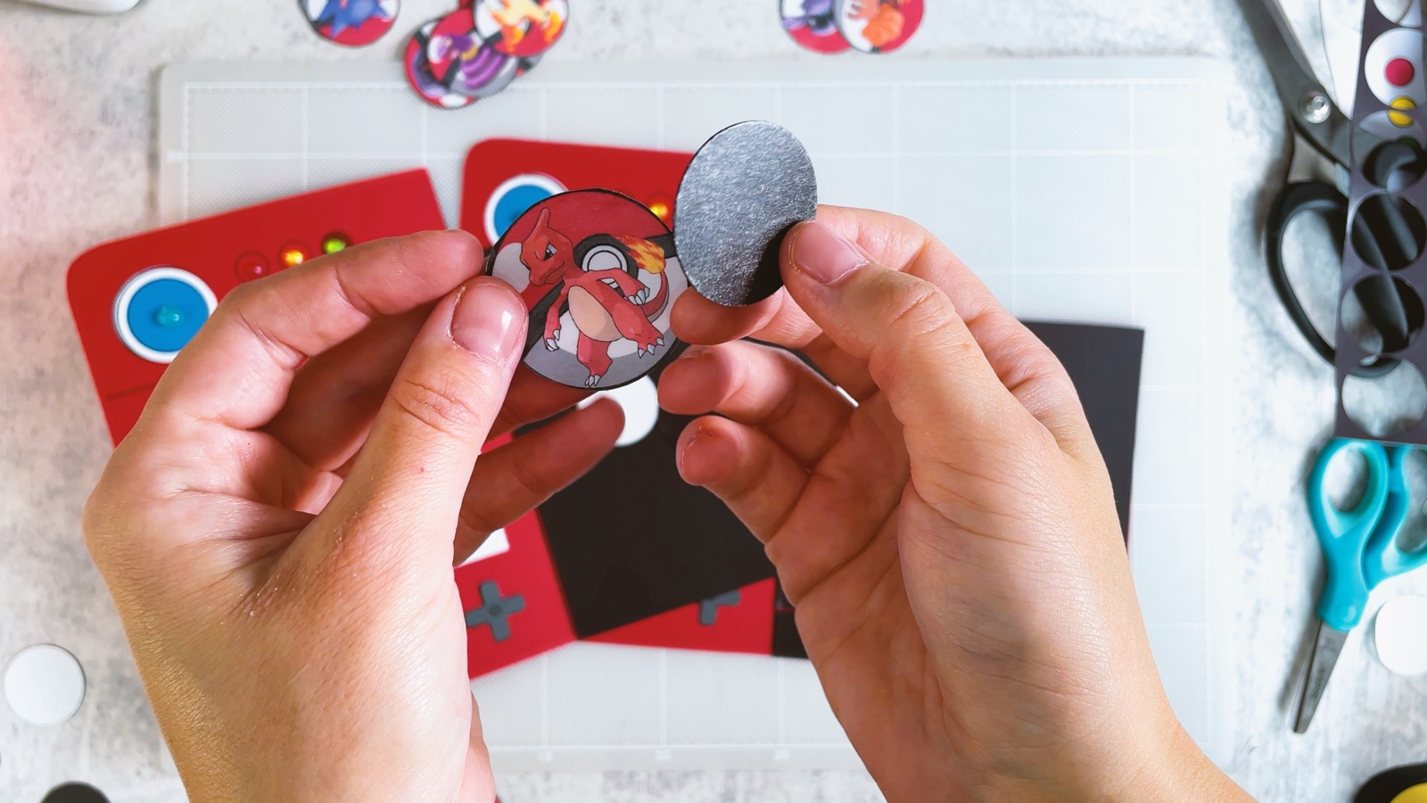 Sosteniendo una ficha de Pokémon y un círculo magnético, a punto de pegarlos