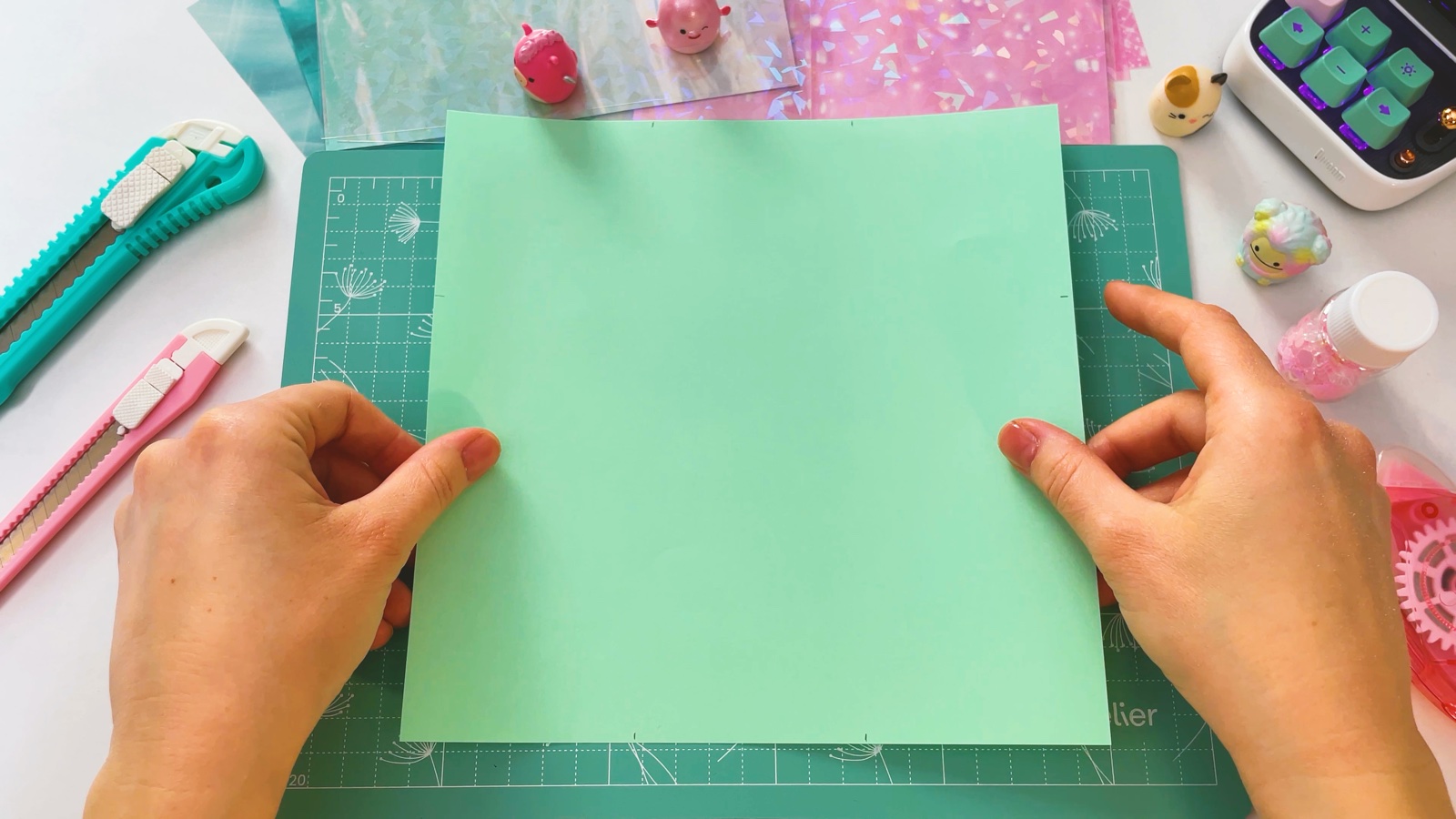 A square sheet of mint green paper lying flat on a cutting mat