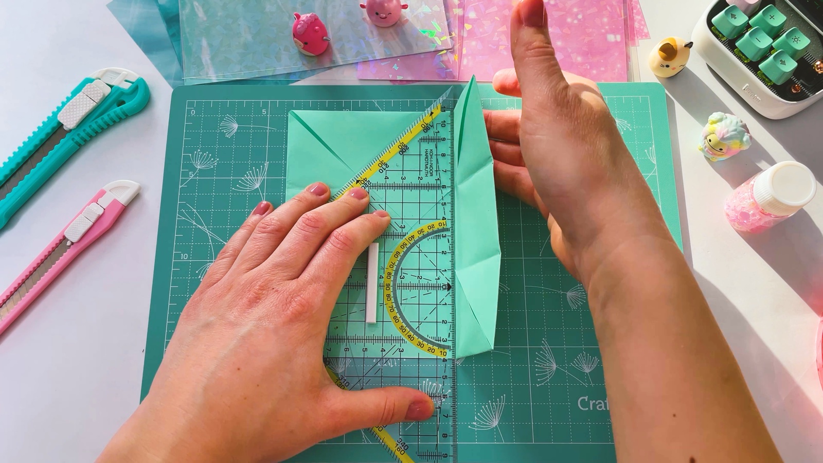 Folding the right edge of the turned paper in towards the middle, with a ruler holding the left half flat