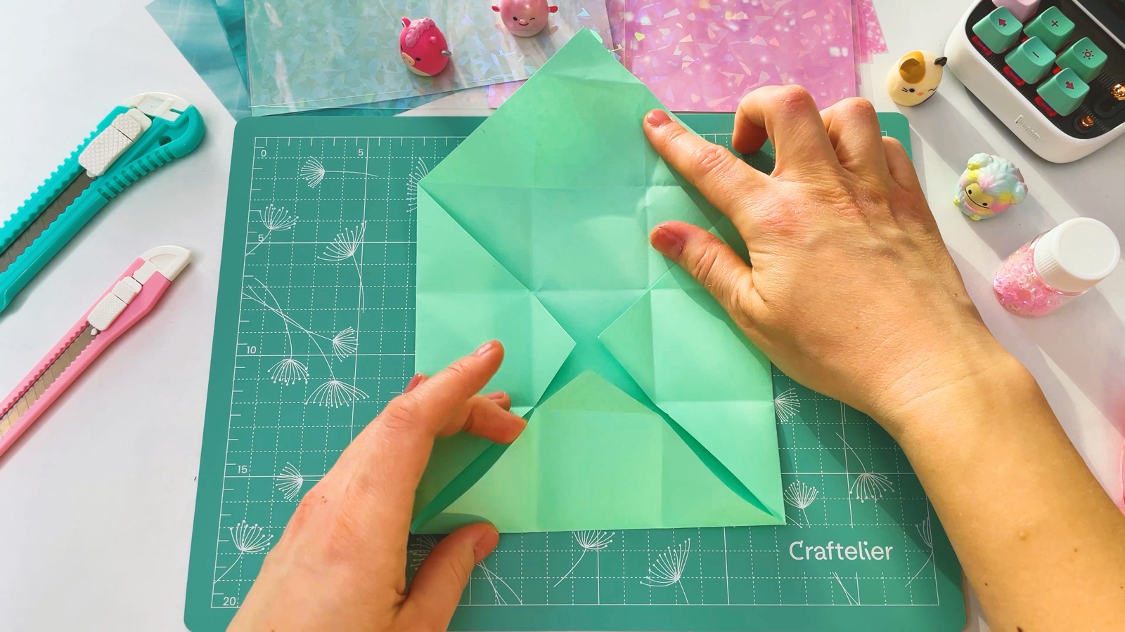 Opening the folded paper flat on the mat, with a grid of creases showing