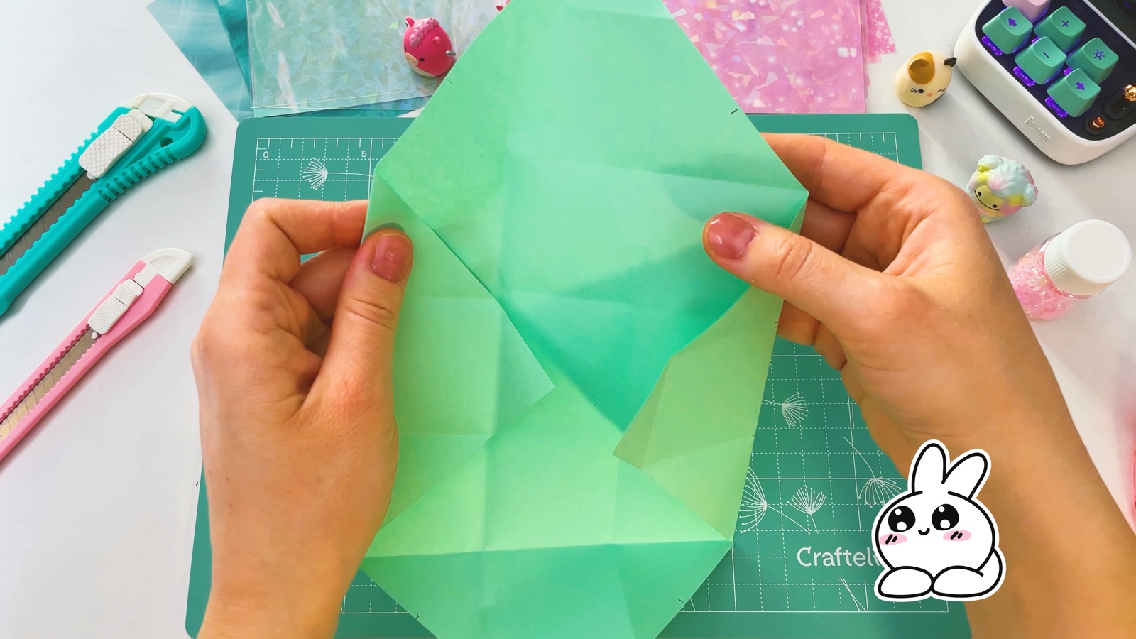 Holding the paper with both hands and lifting two sides up along the creases