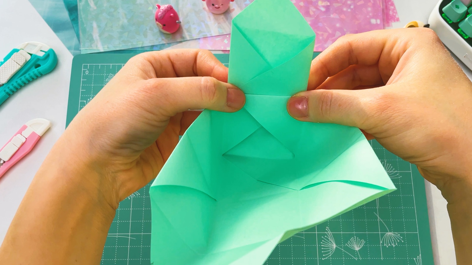 Pinching the corners of one end so it rises up, with a pointed flap standing above the box