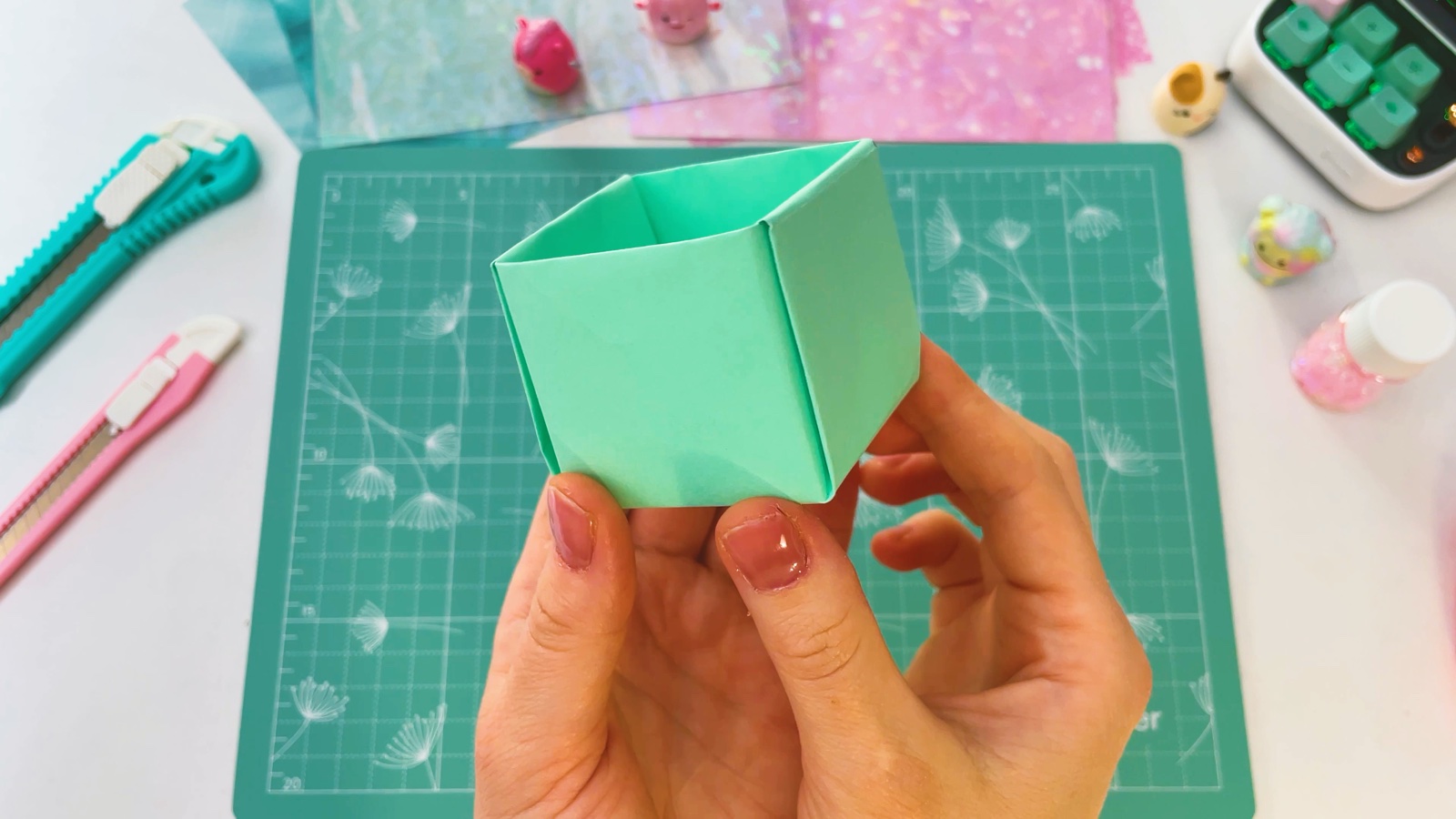 A finished plain green origami box held in one hand
