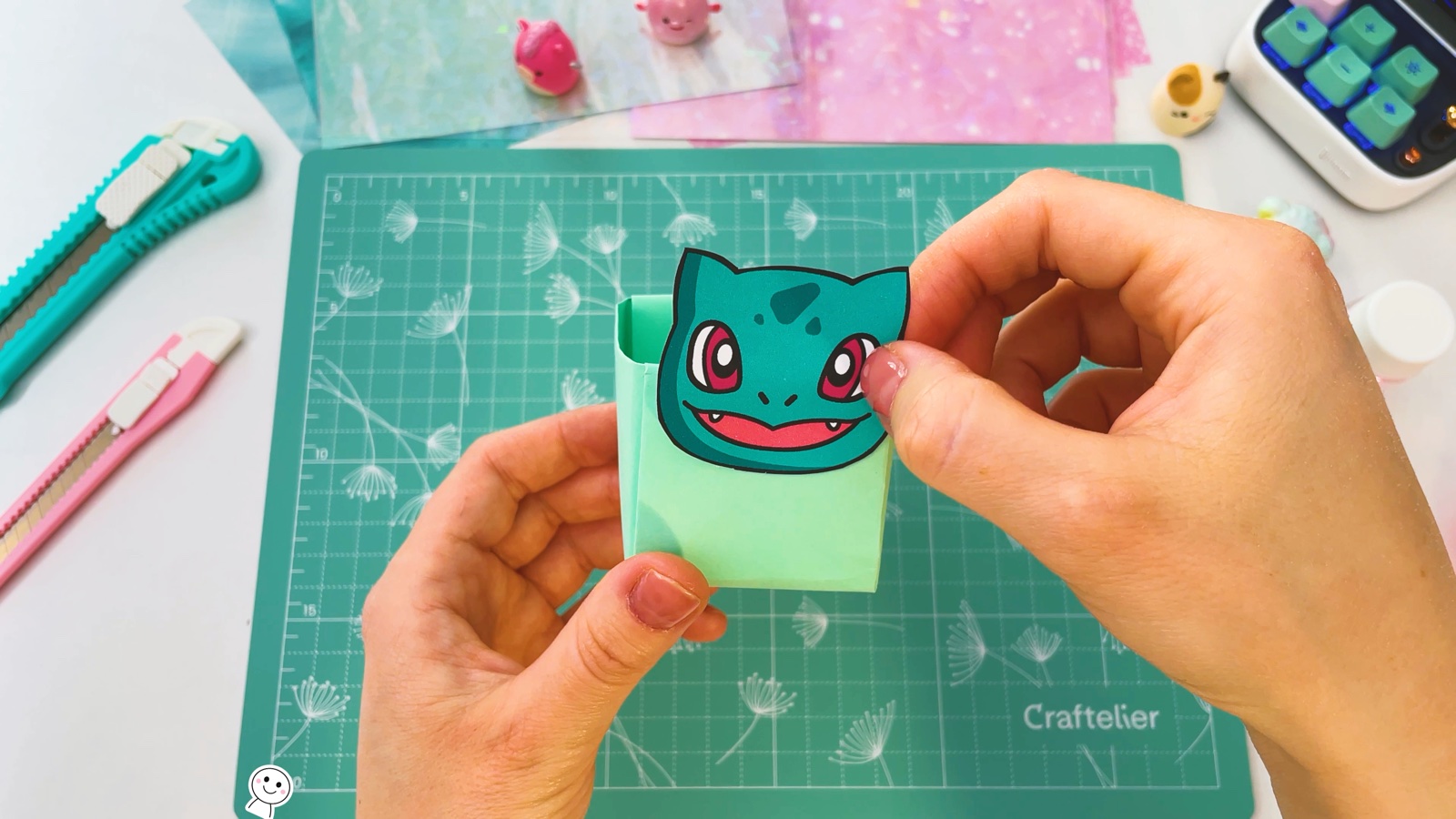 Pressing a paper Bulbasaur face onto the front of the green box