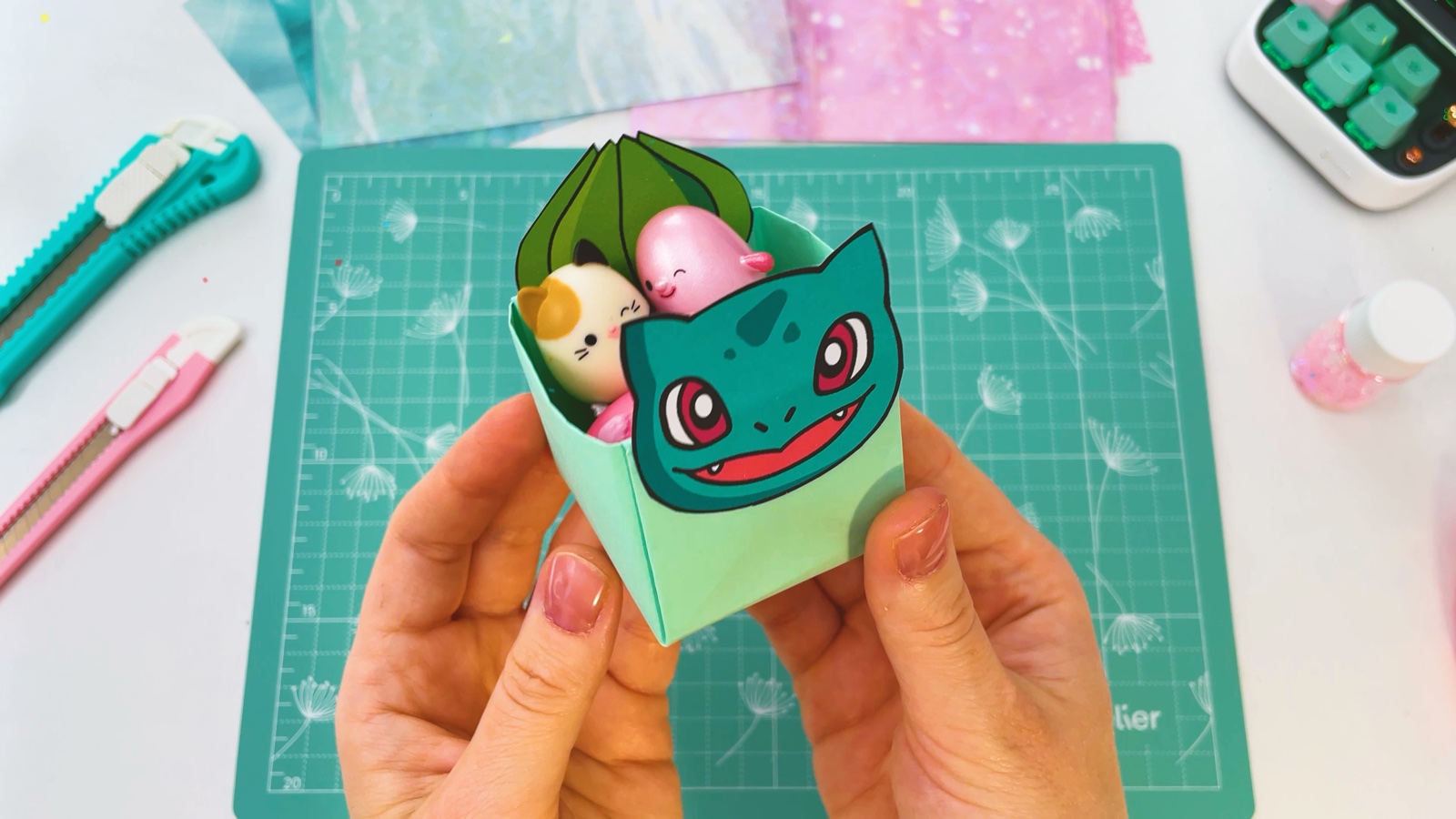 The Bulbasaur box filled with small squishy toys peeking out from behind the face