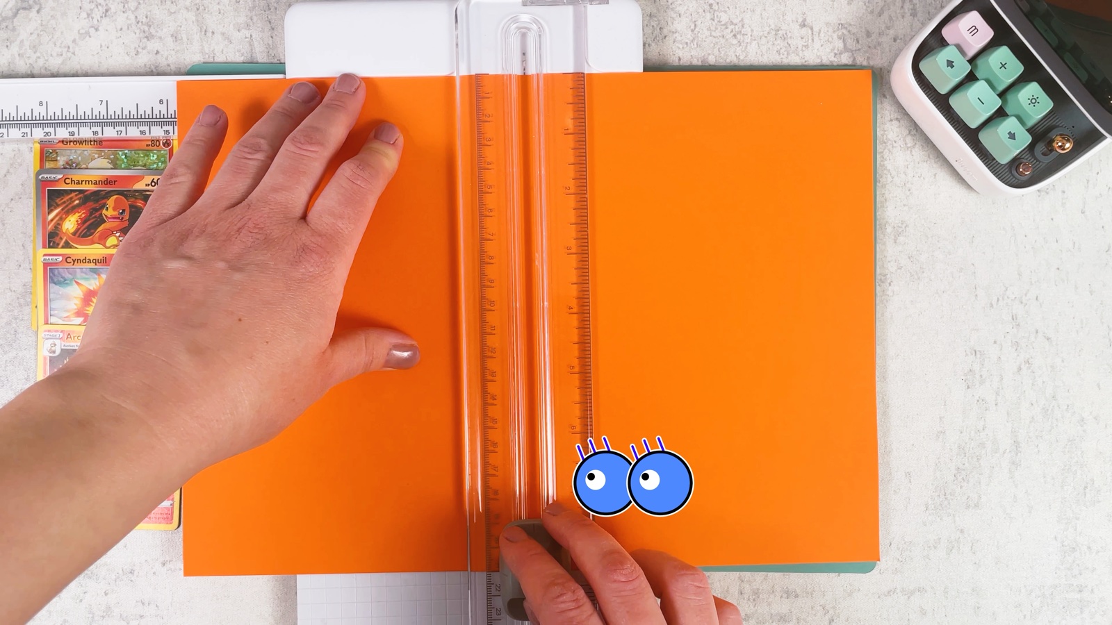 Cutting an orange A4 sheet in half on a paper trimmer