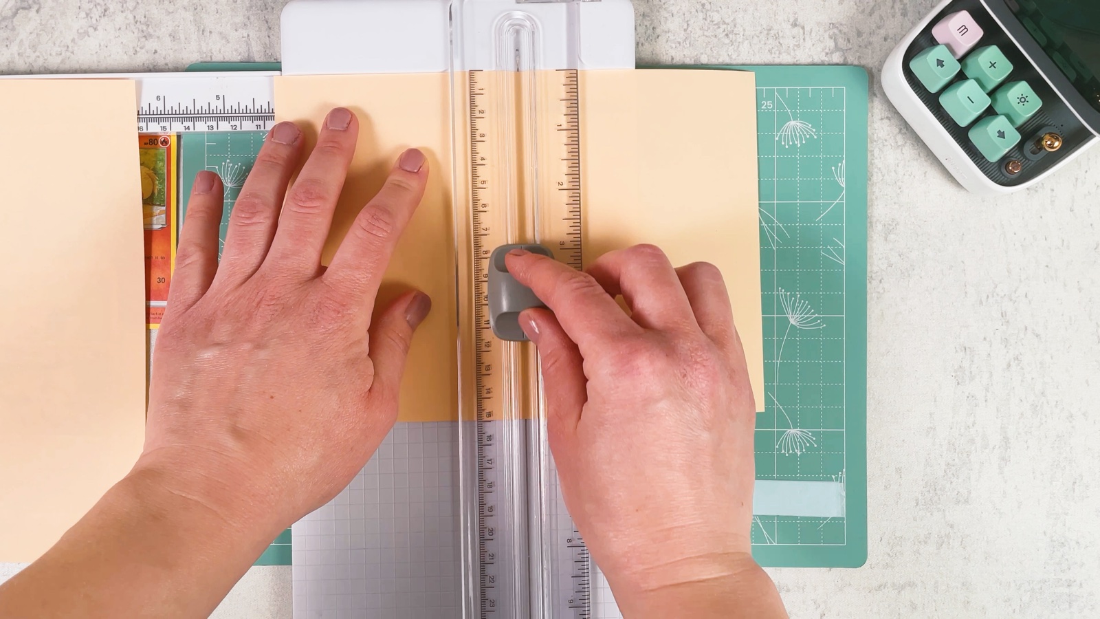 Cutting a sheet of light peach paper into smaller pieces on a paper trimmer