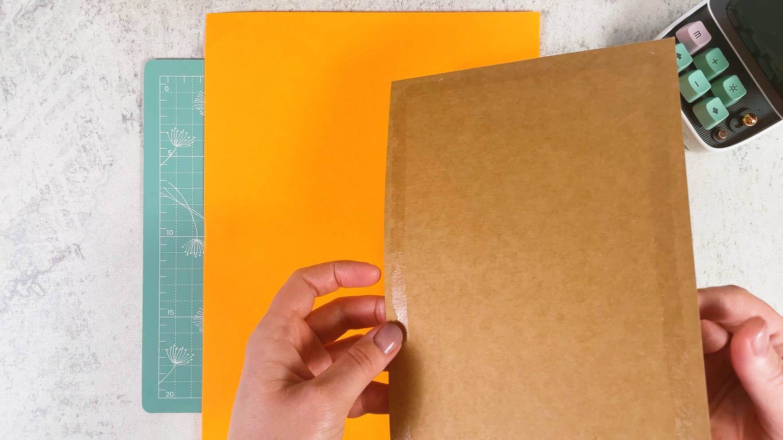 Placing a piece of cardboard onto a sheet of orange paper