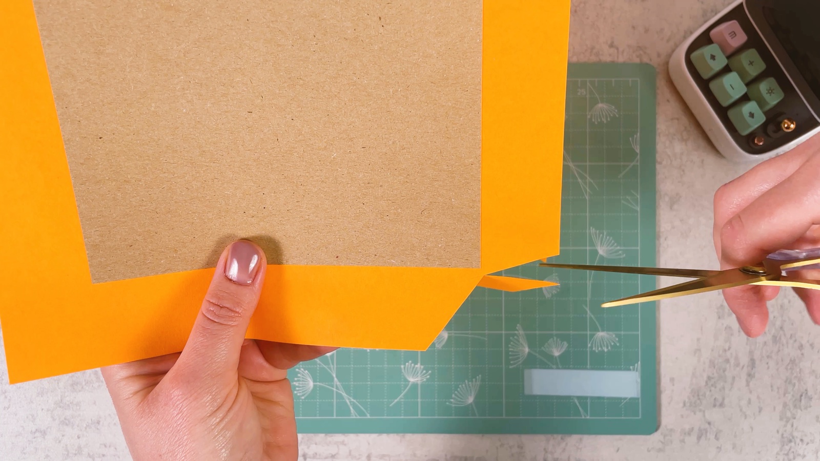 Cutting the corners of the orange paper around the cardboard