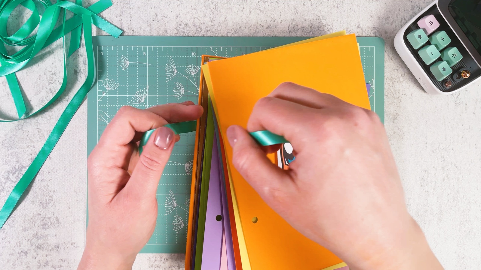 Threading a mint ribbon through the holes of the stacked pages