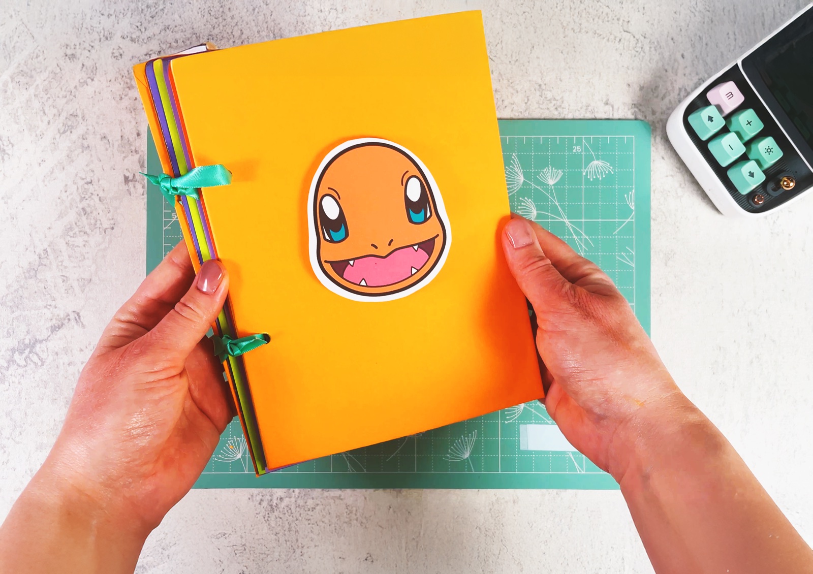 A finished paper Pokémon card binder with an orange cover and a Charmander face