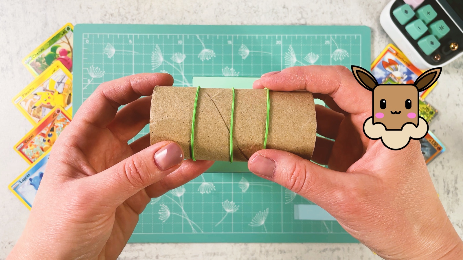 A toilet paper roll with three green rubber bands wrapped around it
