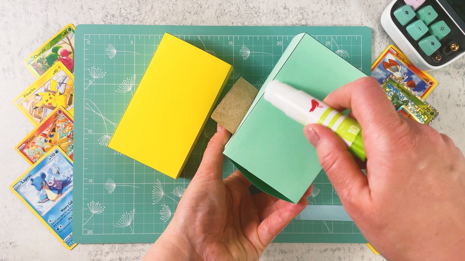Putting glue on the mint box next to the yellow base