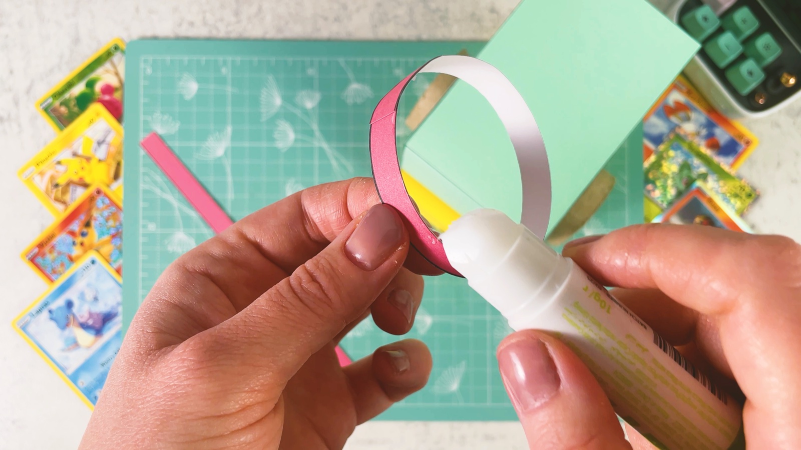 Gluing a red paper strip around the edge of a Poké Ball