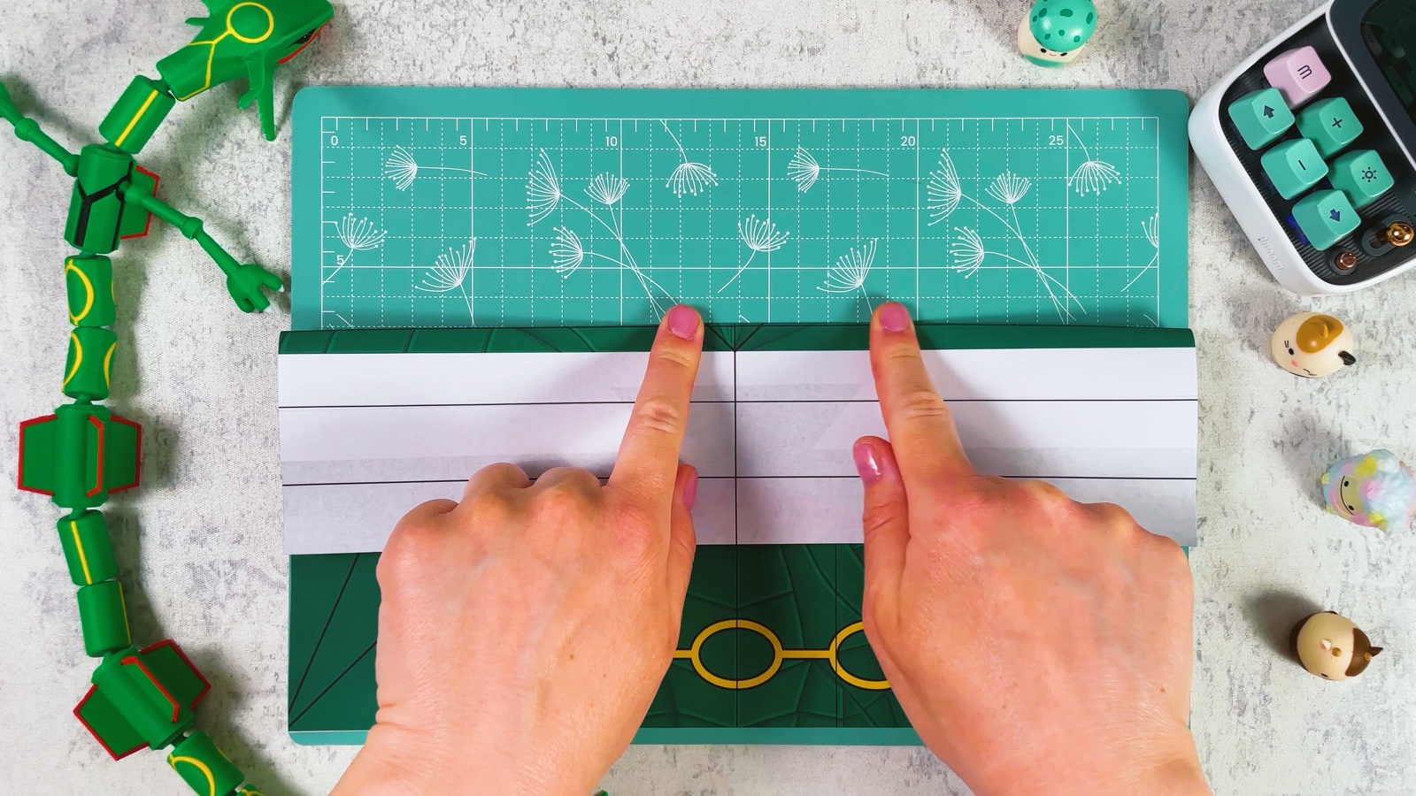 Two fingers pressing a fold along the white strip at the top of the sheet, with the yellow rings below