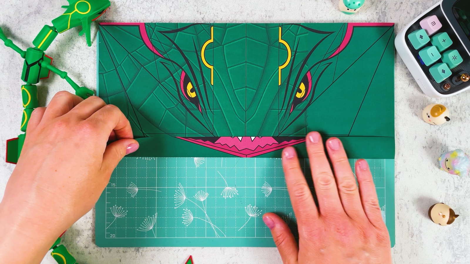 Pressing the folded strip flat, with the pink mouth now showing just below Rayquaza’s eyes