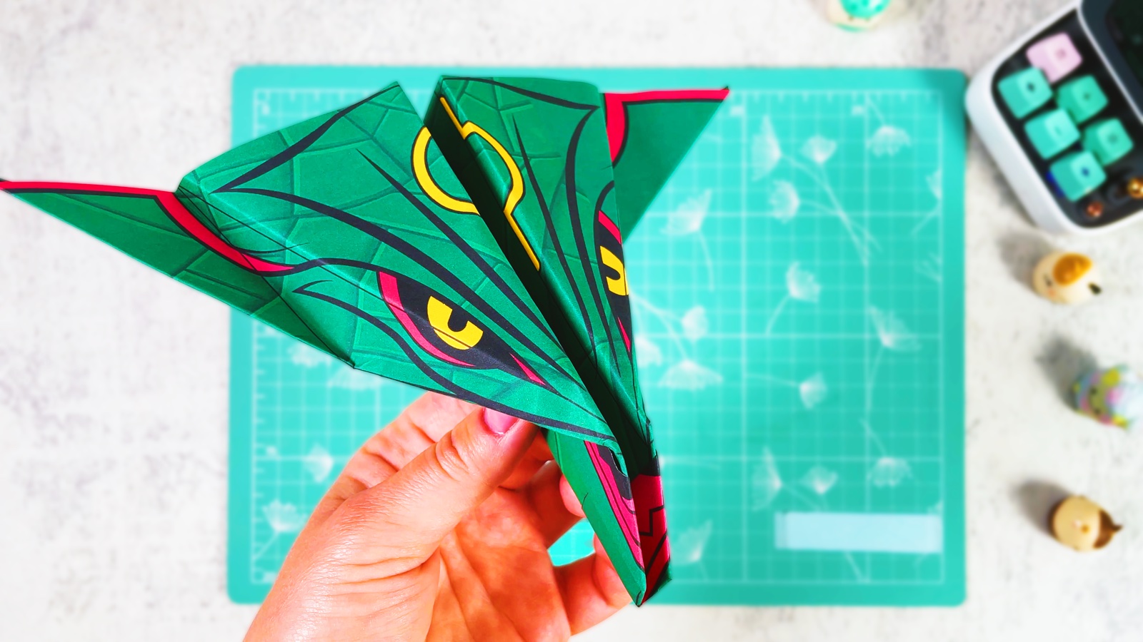 A finished green Rayquaza paper airplane with yellow rings and red-rimmed eyes