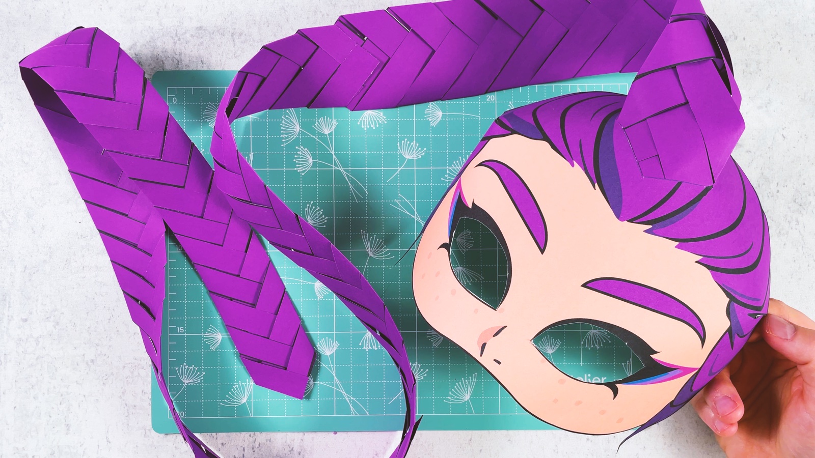 Finished paper Rumi mask with purple hair and a long folded paper braid