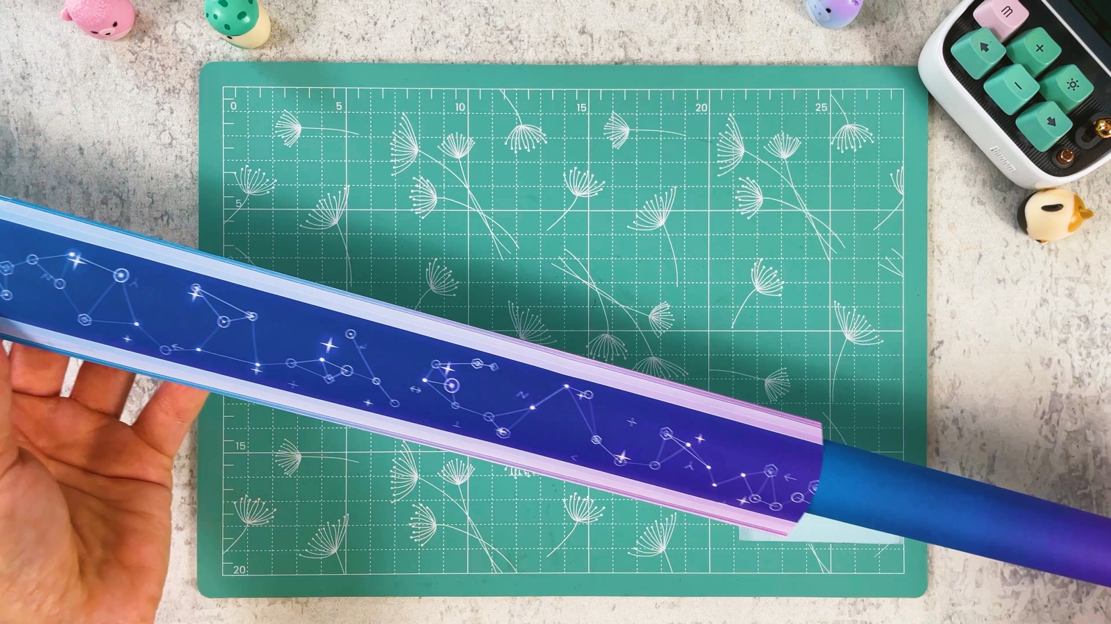 La lame violette et bleue étoilée, fermée, avec le tube en dégradé qui dépasse comme poignée