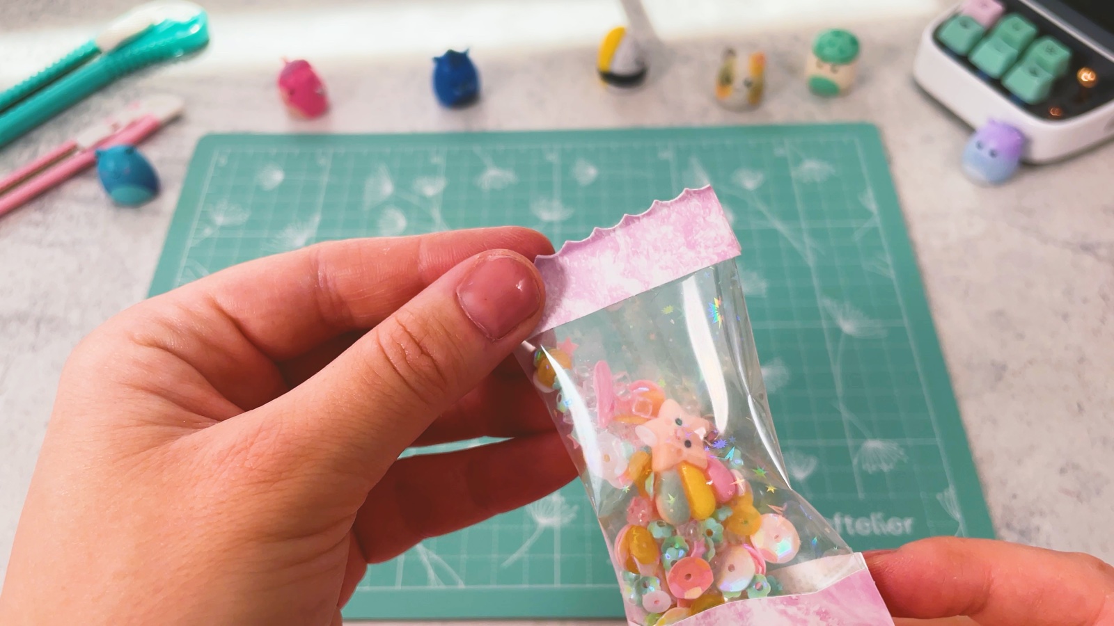 Das verschlossene Shaker-Täschchen in der Hand, mit welligen rosa Papierenden auf beiden Seiten, innen Pailletten und ein Sternanhänger