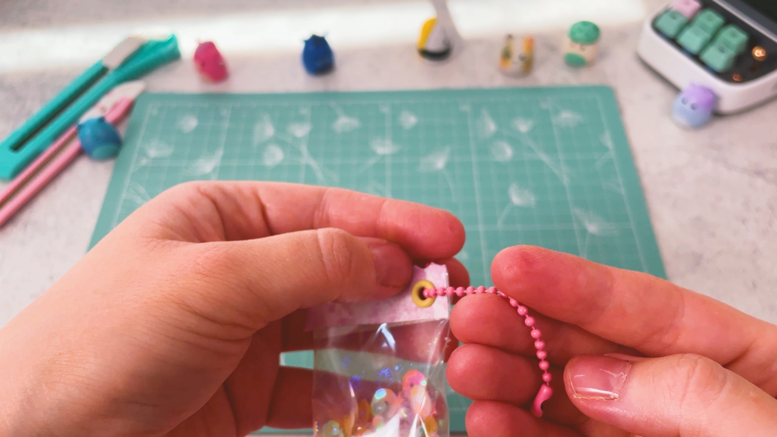 Die rosa Kugelkette ist durch die gelbe Öse in der Ecke des Shakers gefädelt