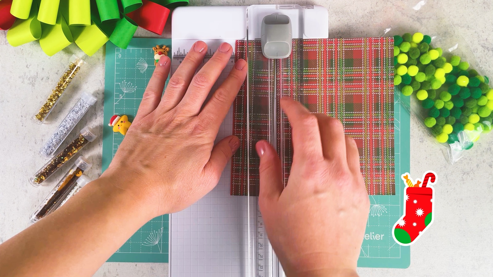 Cutting a sheet of red and green plaid paper with a paper trimmer