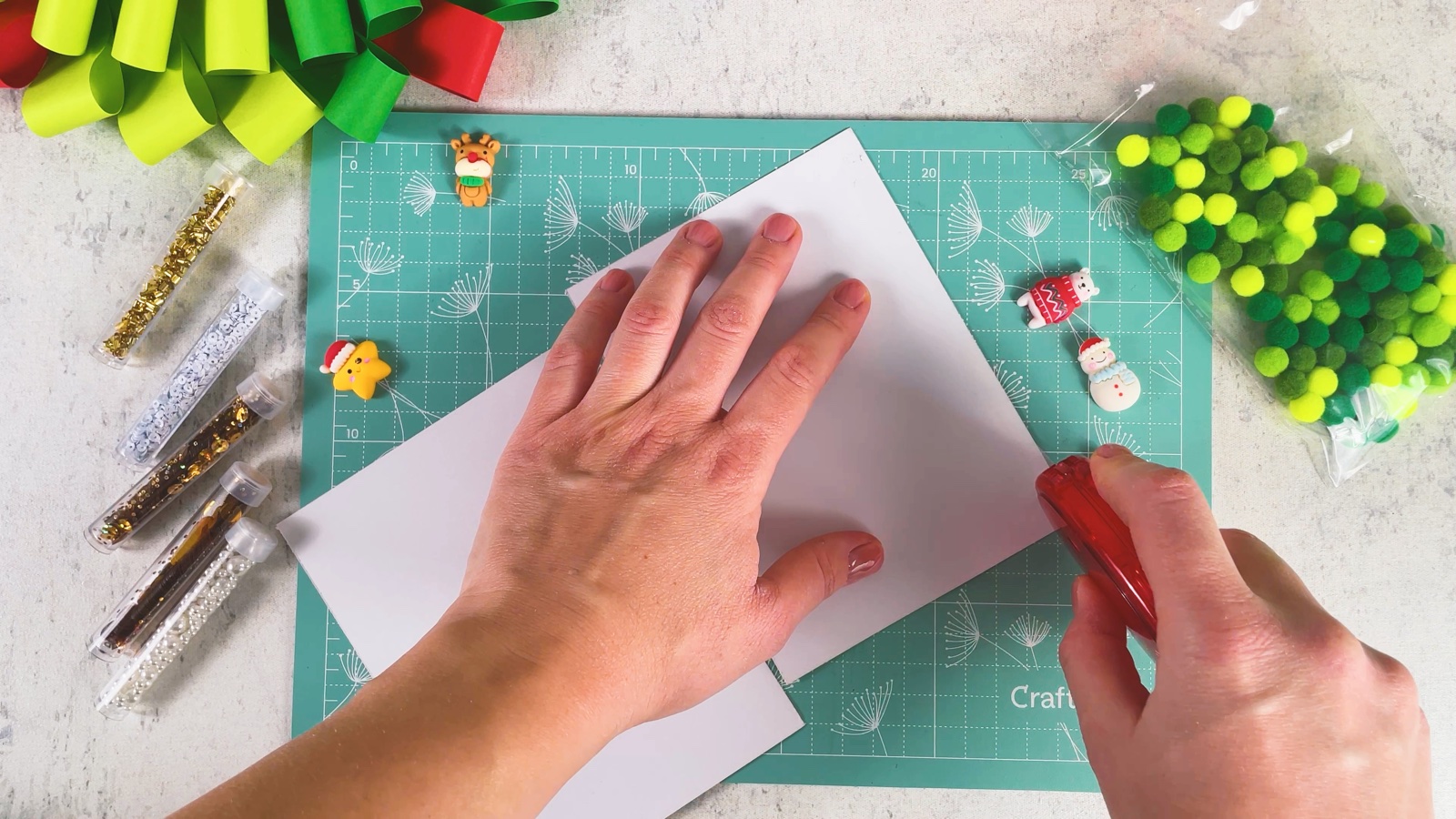 Smoothing a sheet of double-sided tape onto the back of the paper, with a red tape roller nearby