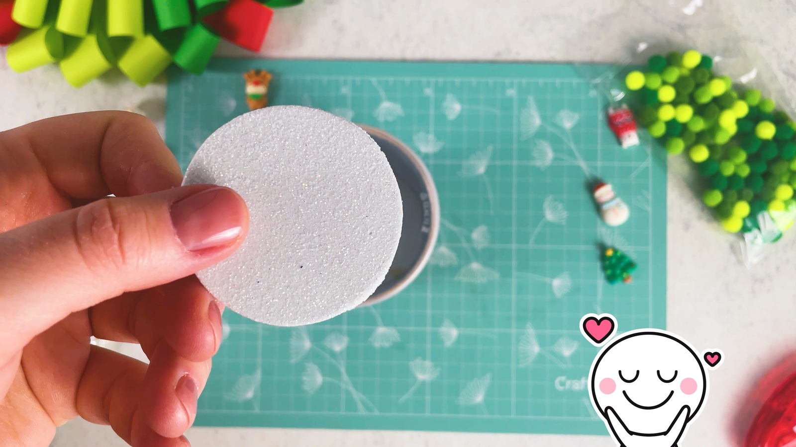 Holding the punched silver glitter foam circle, with the circle punch behind it