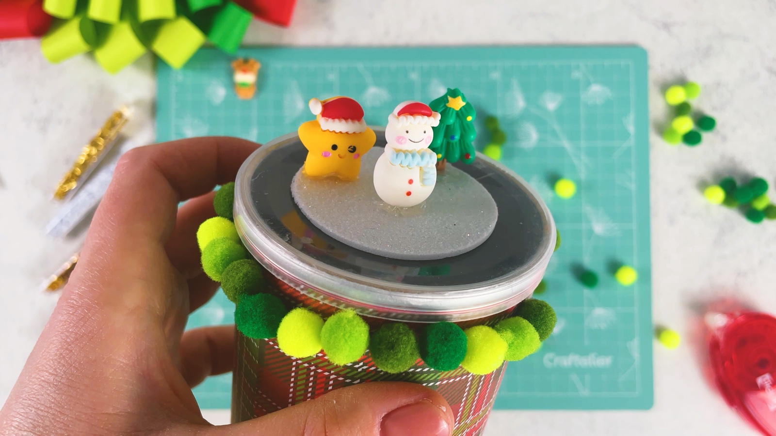 Placing a tiny Christmas tree next to a snowman and a gingerbread figurine on the glitter circle