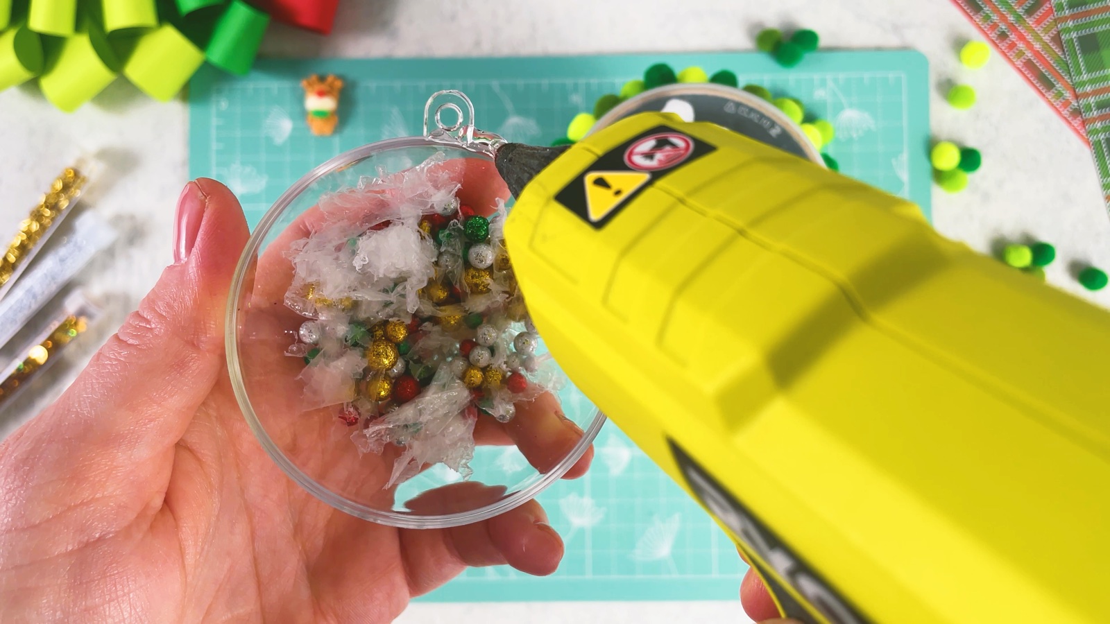 Putting hot glue around the rim of the filled bauble half