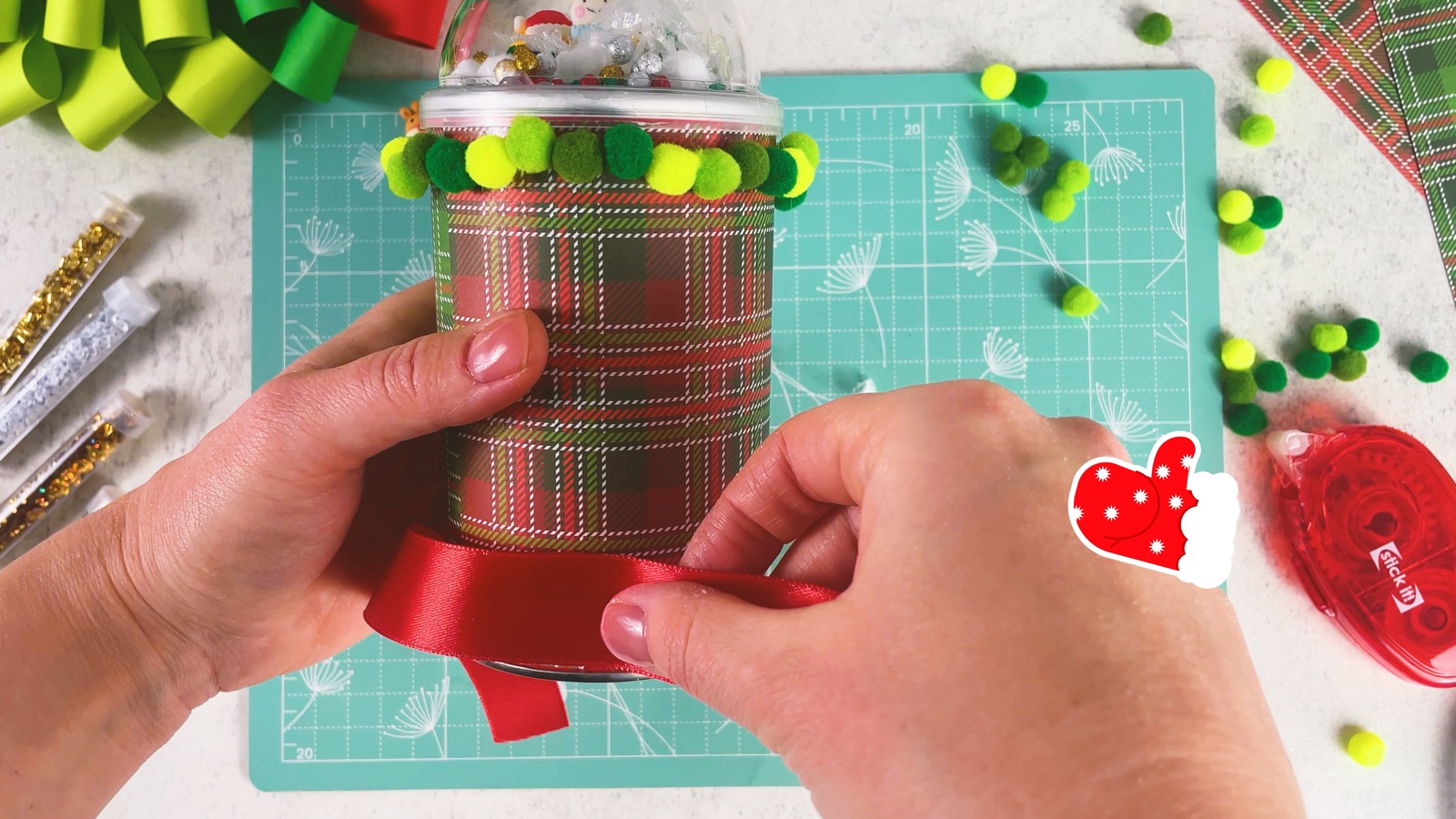 Wrapping a red satin ribbon around the bottom of the can