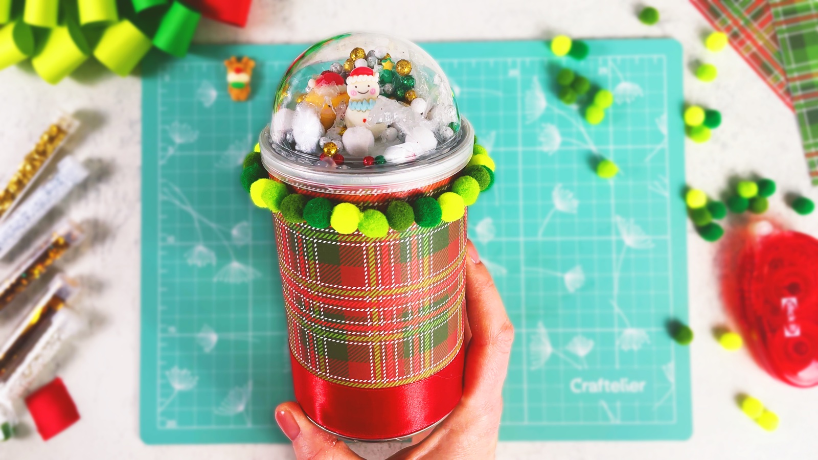 A finished snow globe gift box made from a plaid-wrapped Pringles can