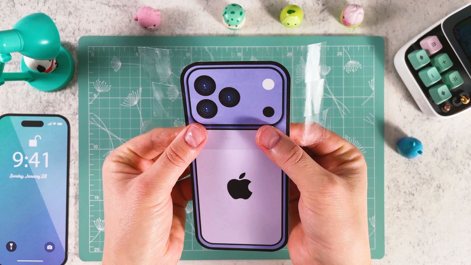 Smoothing a strip of clear packing tape over the purple back of the phone
