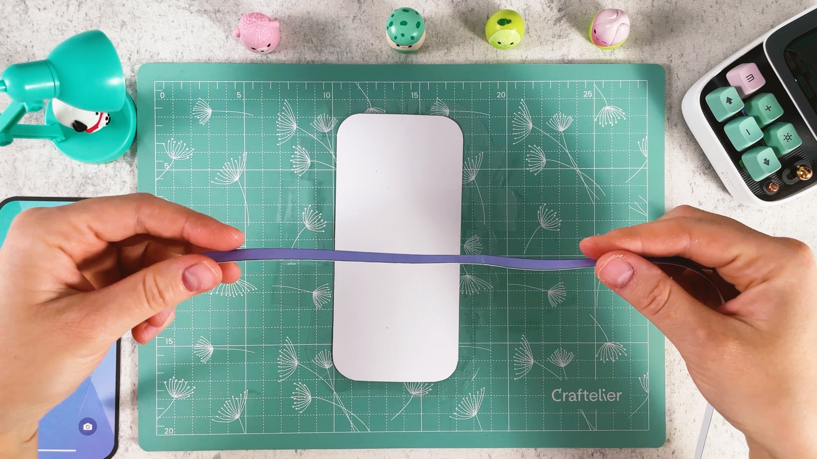 Holding the long purple strip across the white side of the phone back