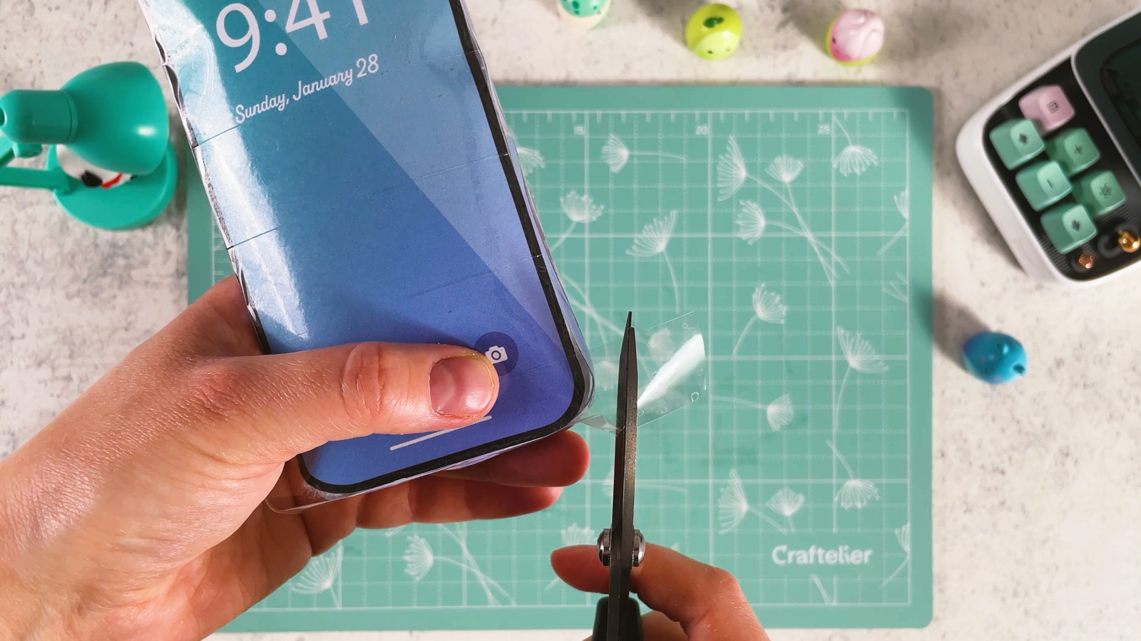 Trimming extra tape off the edge of the closed, puffy phone