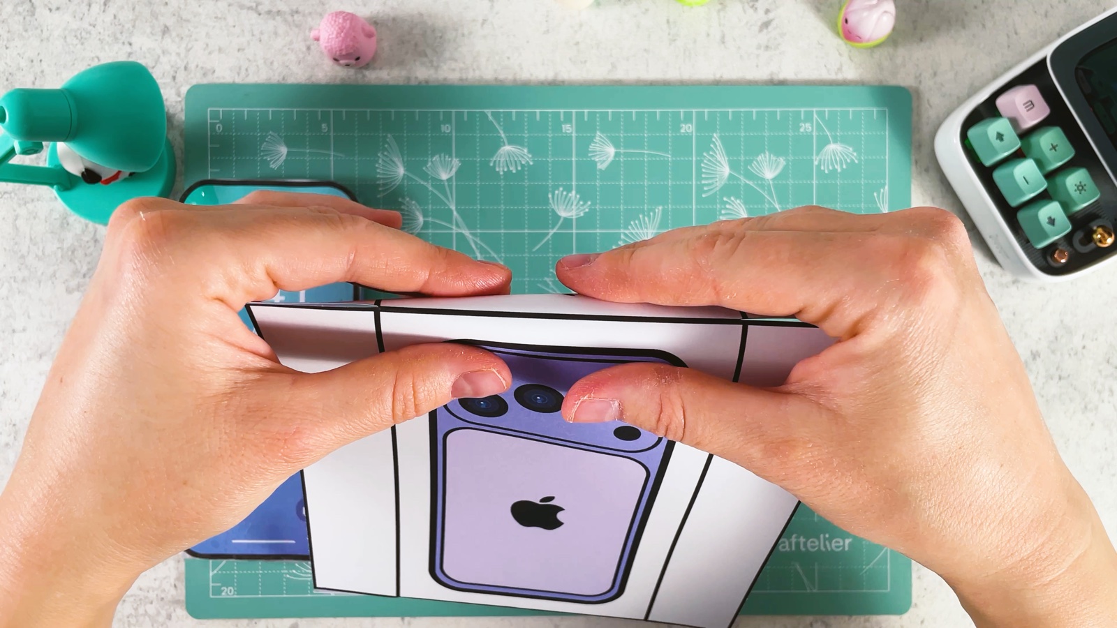 Pressing the top side of the box lid down along its fold line, with the purple iPhone picture facing up