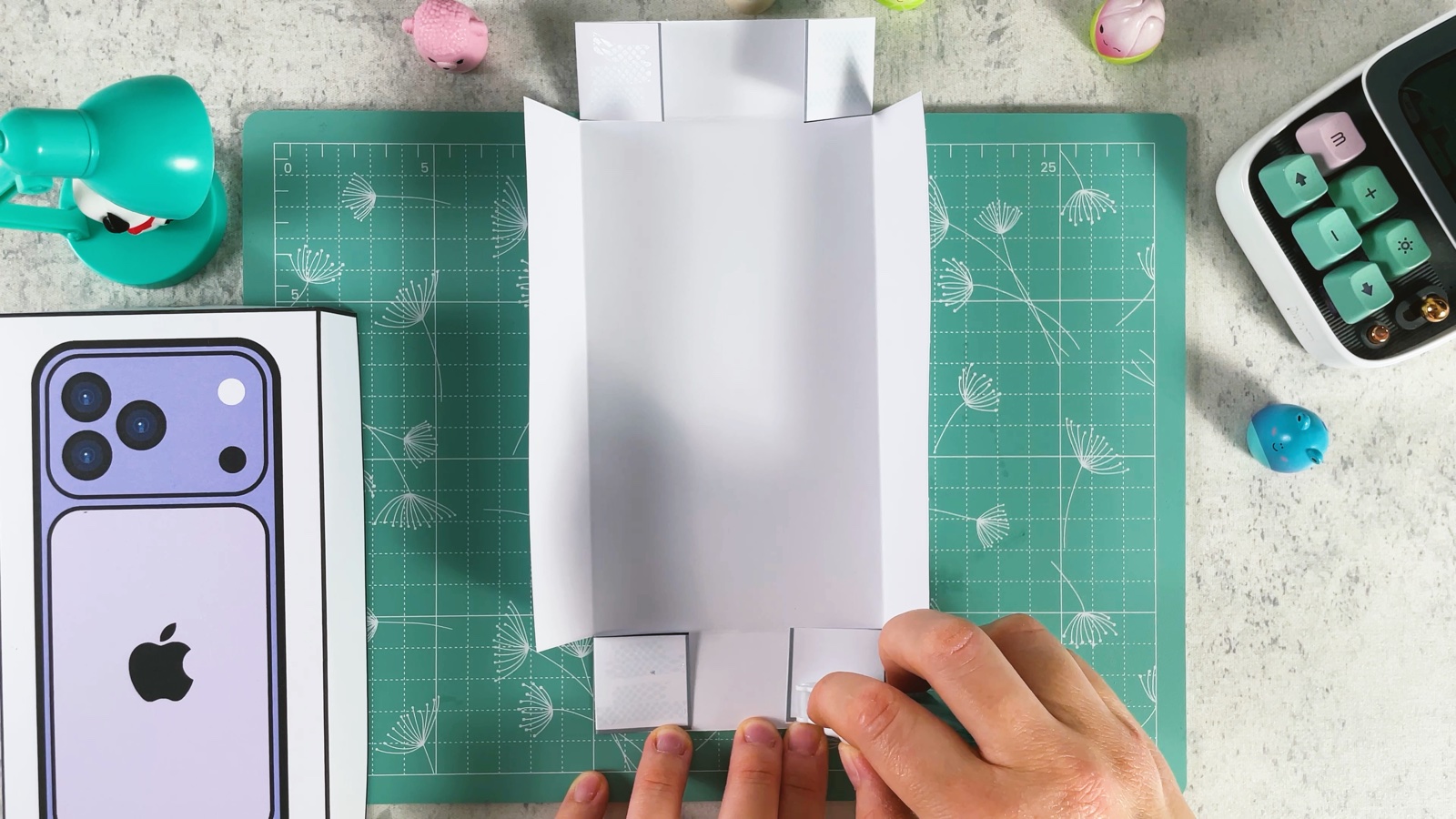 The plain box bottom with its long sides folded up and the corner flaps ready to glue