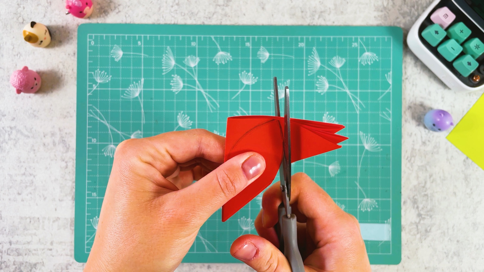 Cutting the petal shape through the folded red layers with scissors