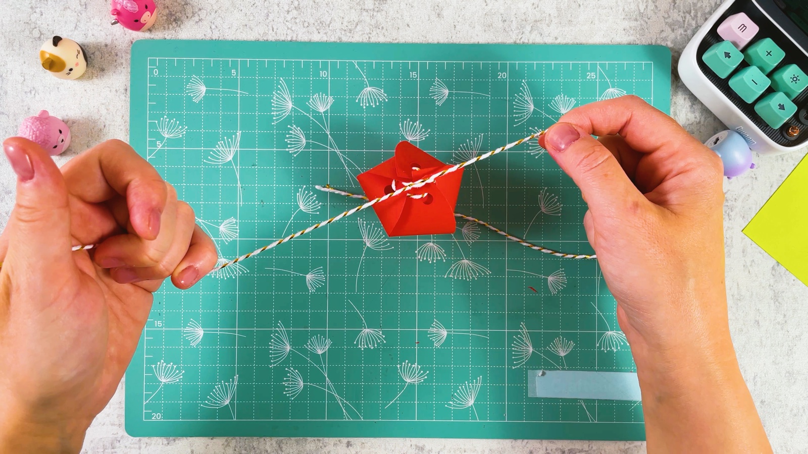 Pulling both ends of the string so the red petals close into a strawberry shape